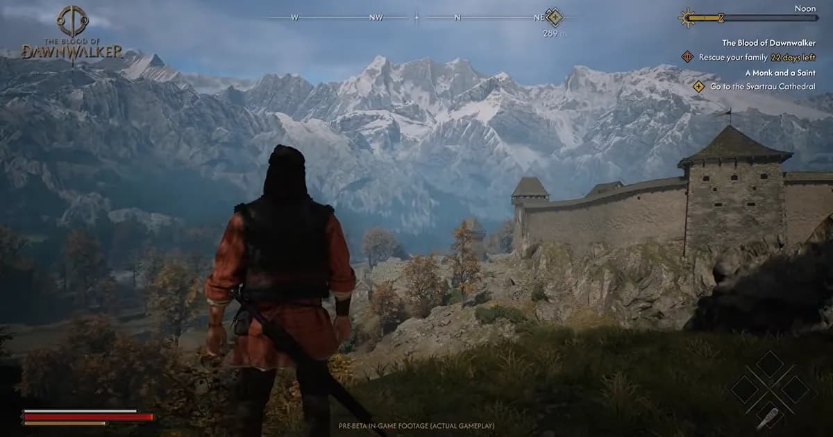 A lone traveller overlooks a medieval fortress and a vast mountain range in broad daylight.
